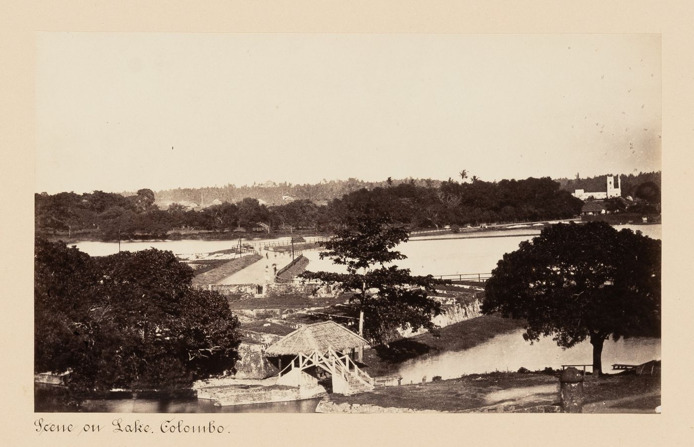 View of a lake showing a footpath, fortifications and a footbridge, Colombo, Ceylon (now Sri Lanka)