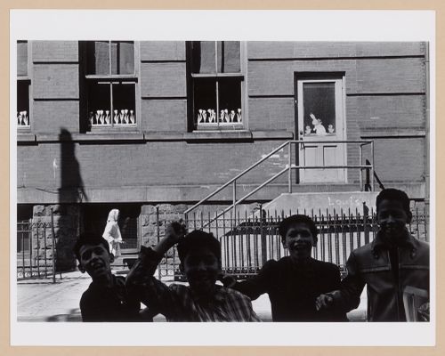 Partial view of a façade of a school [?] with children laughing in the foreground, Hoboken
