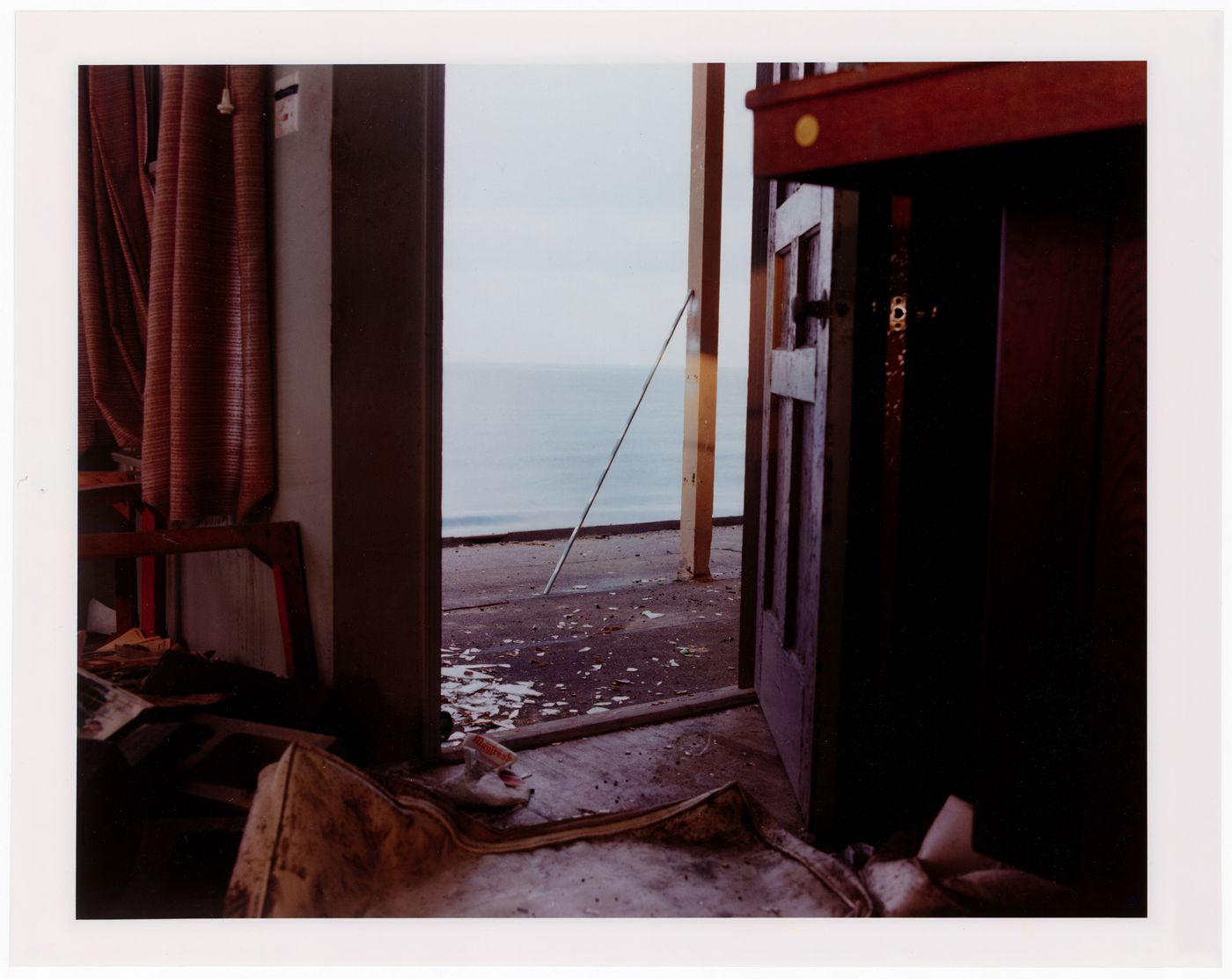 Abandoned beach house, close-up of open door with cushion on floor, California ?