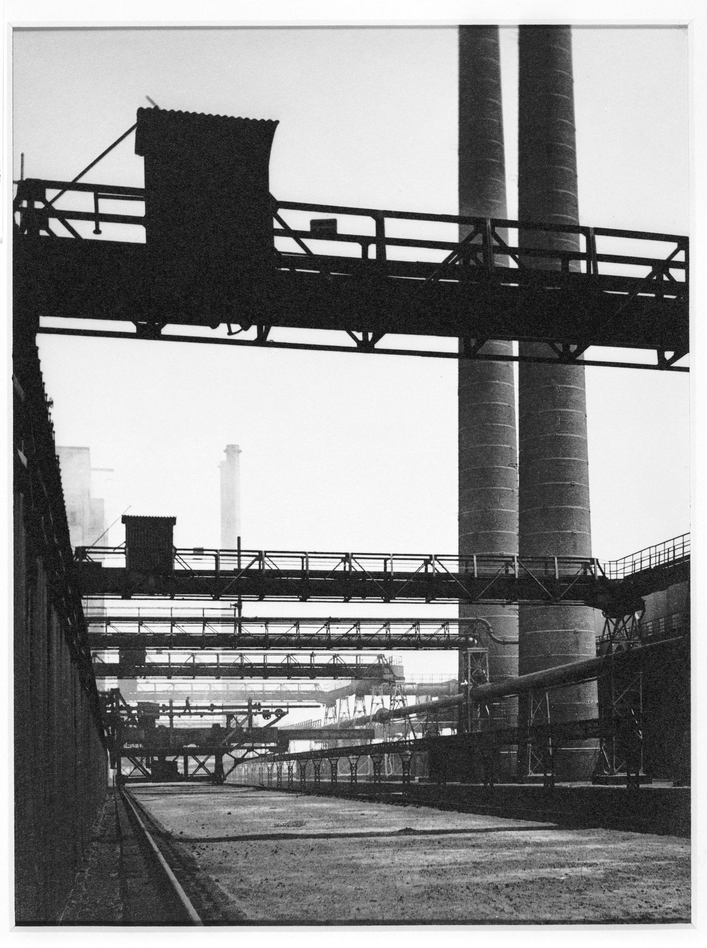 Unidentified industrial site, with two tall chimneys at right