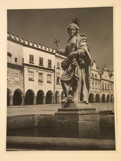 Partial view of a fountain with a statue in the Námestí Míru [Town Square] with buildings in the background, Telc, Czechoslovakia (now Czech Republic)