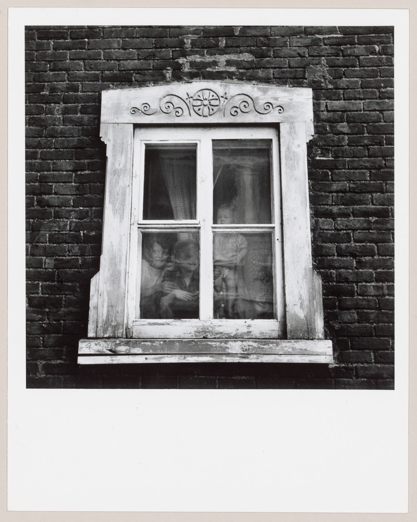 Enfants de la famille Arsenault  vus à travers la fenêtre de leur maison,  L'Islet-sur-Mer, Québec
