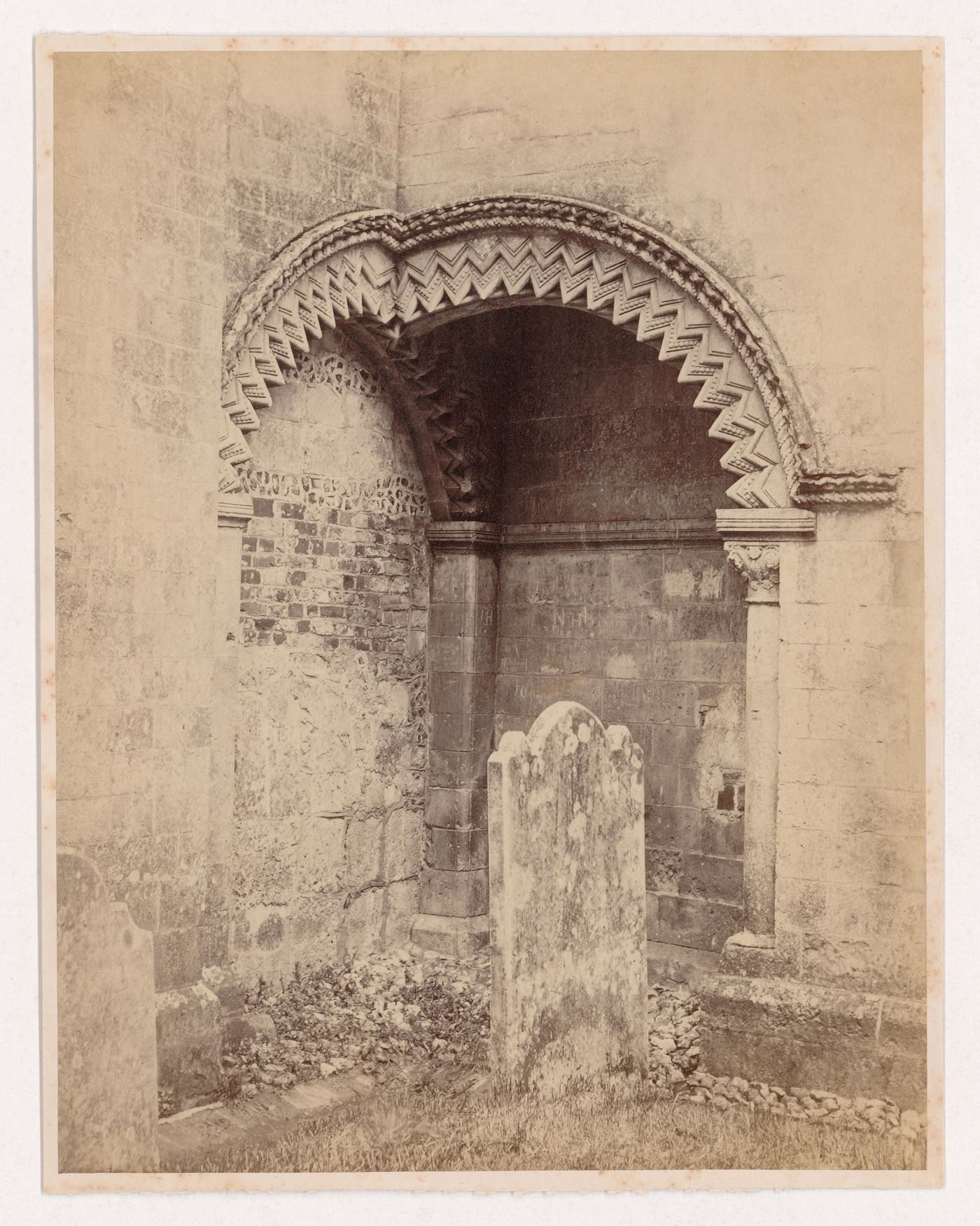 View of two intersecting arches on the exterior of a church with a tombstone in the foreground, England
