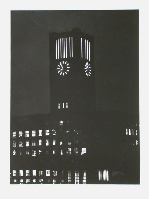 Night view of illuminated clock tower on large building, Berlin, Germany