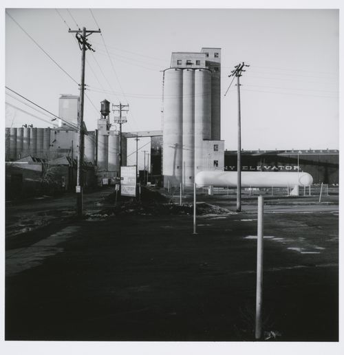 Grain elevator complex with telephone poles and parking lot in foreground, Minneapolis, Minnesota