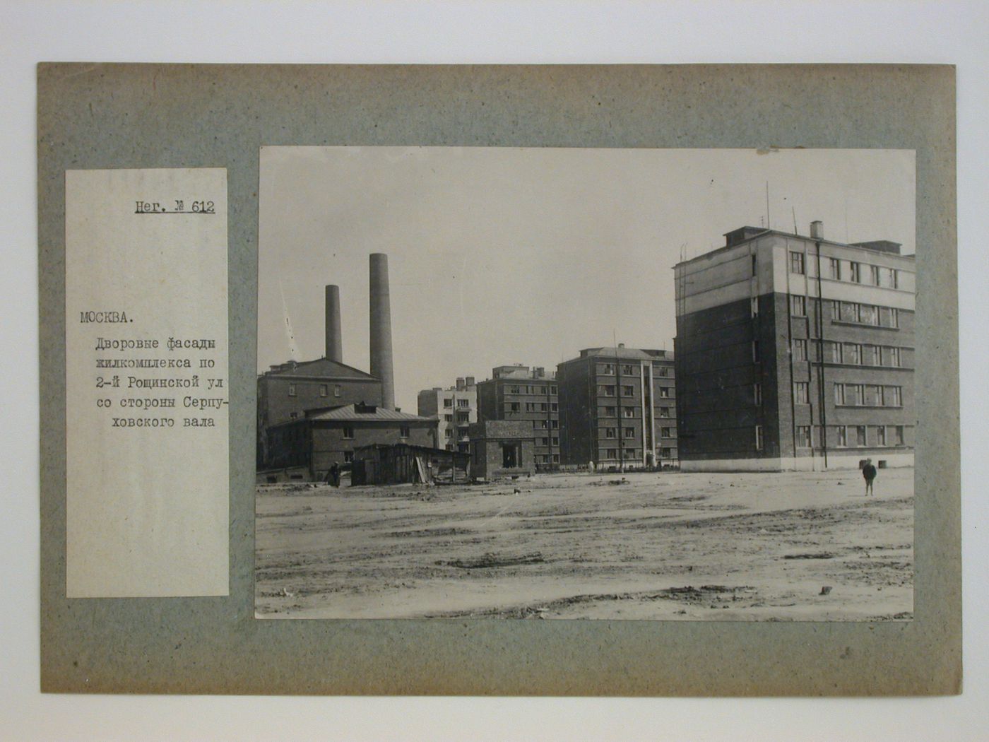 View of housing in the Serpukhovkii complex with smokestacks and a factory [?] on the left, 2nd Roshchinskaia Street, from Serpukhovskii Val, Moscow, Soviet Union (now in Russia)