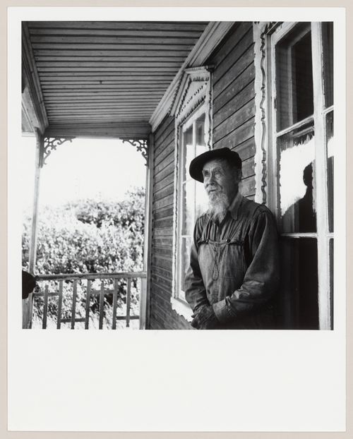 Portrait de l'artisan Servule Morneau sur le portique de sa maison, Saint-Jean-Port-Joli, Québec