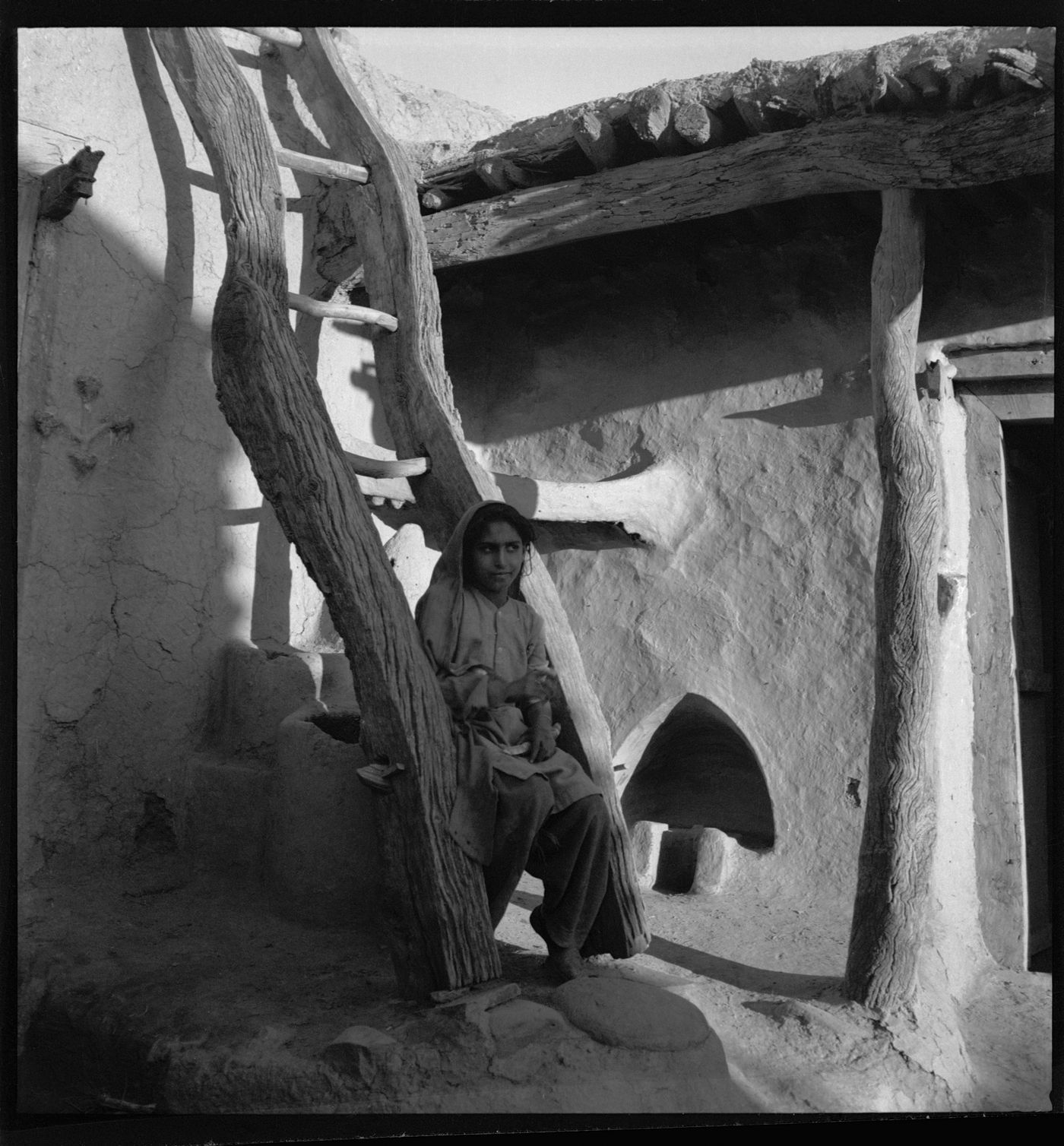 Woman sitting on the wood ladder of a rural house in Chandigarh's area before the construction, India
