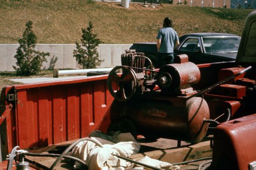 Photograph of paint sprayer and compressor in the back of a truck for Red Line