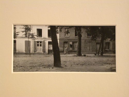Woman standing next to brick buildings, trees in foreground