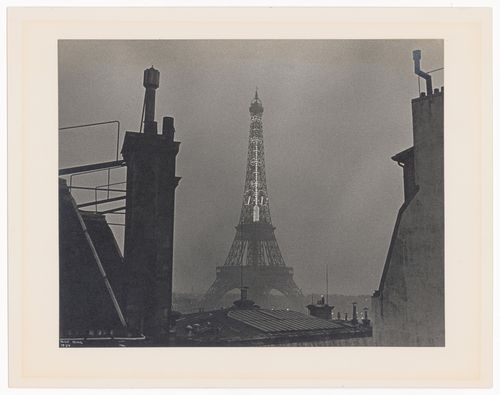 Eiffel Tower with lit thermometer, seen at night, bordered by building rooves (No. 6), Paris, France