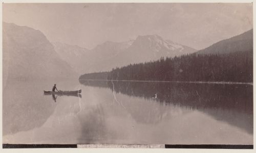 View of Lake Minnewanka (Devil's Lake) with a canoeist in the foreground and mountains in the background, Banff, Alberta