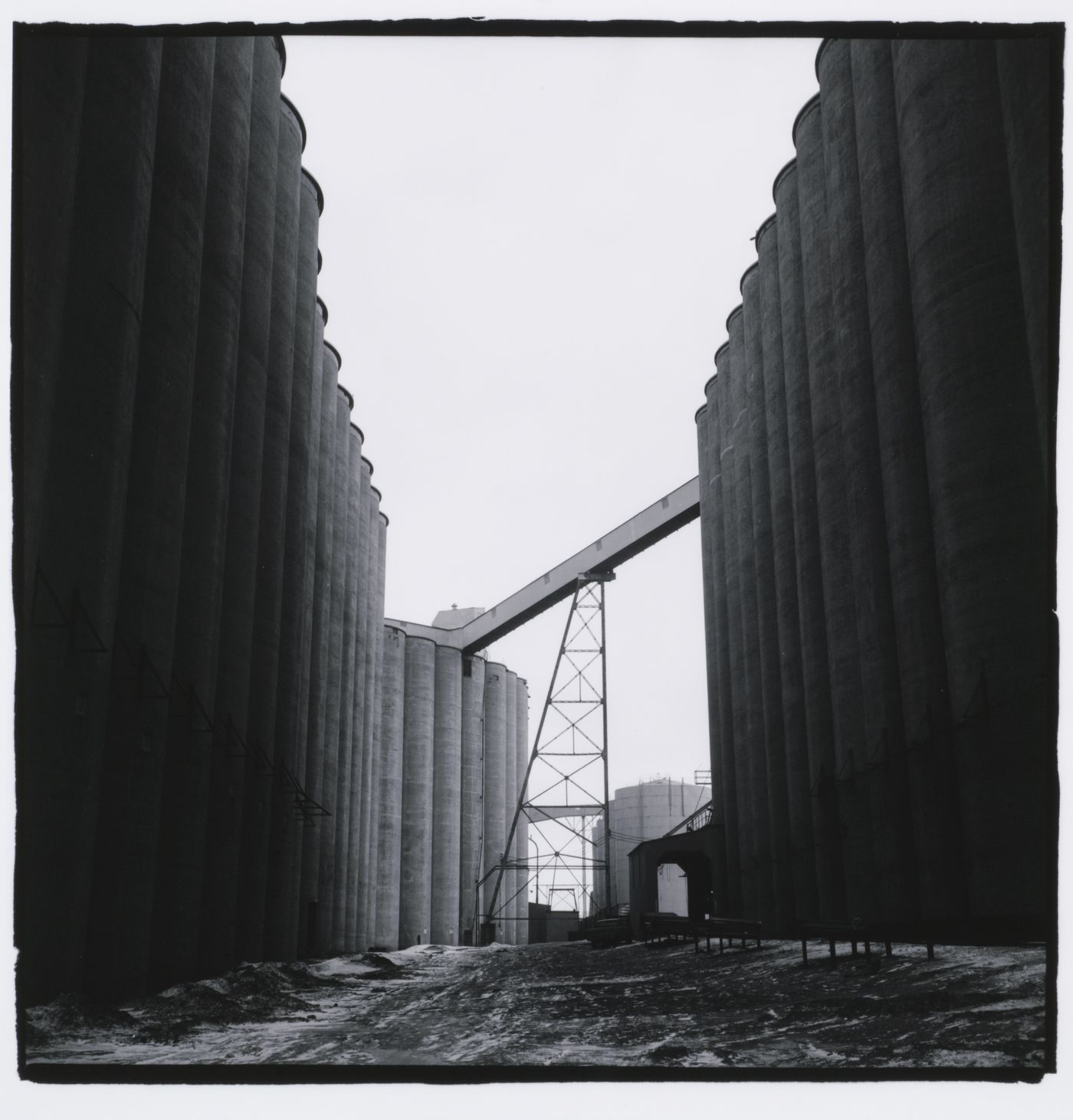 Looking down corridor between rows of tall tube- shaped grain elevators, Minneapolis, Minnesota