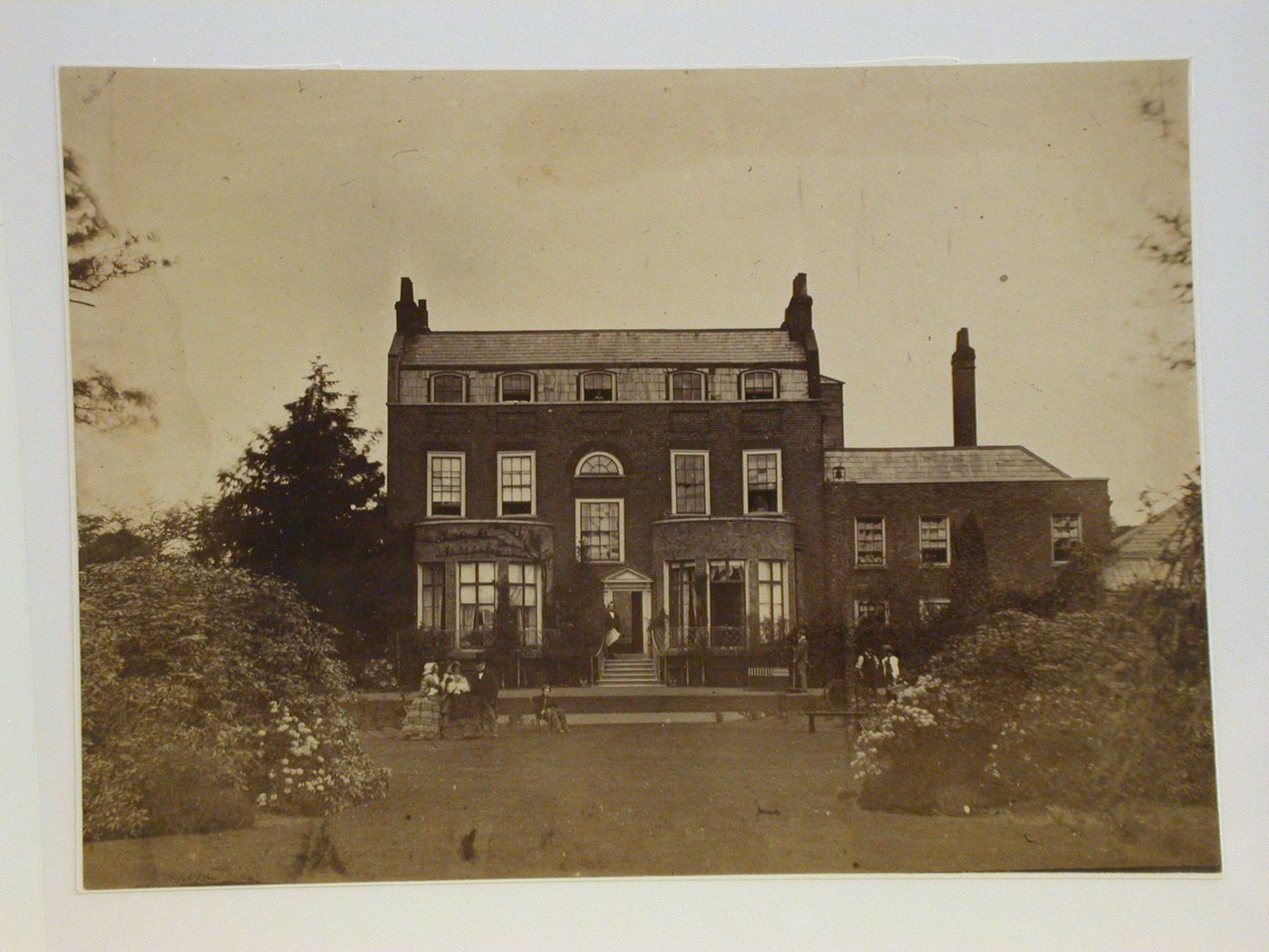 View of a house from the back, with 8 people in the garden, England ?