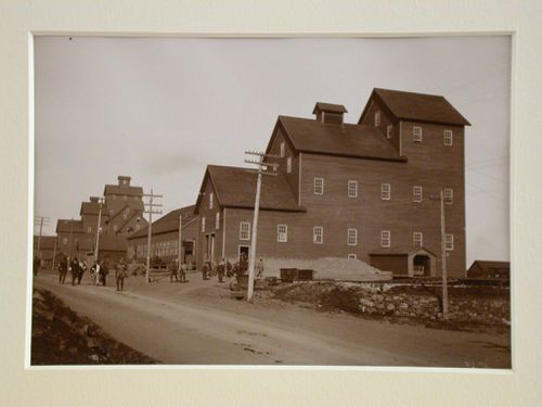 View of wooden mine shafts from road, workers leaving building and on road