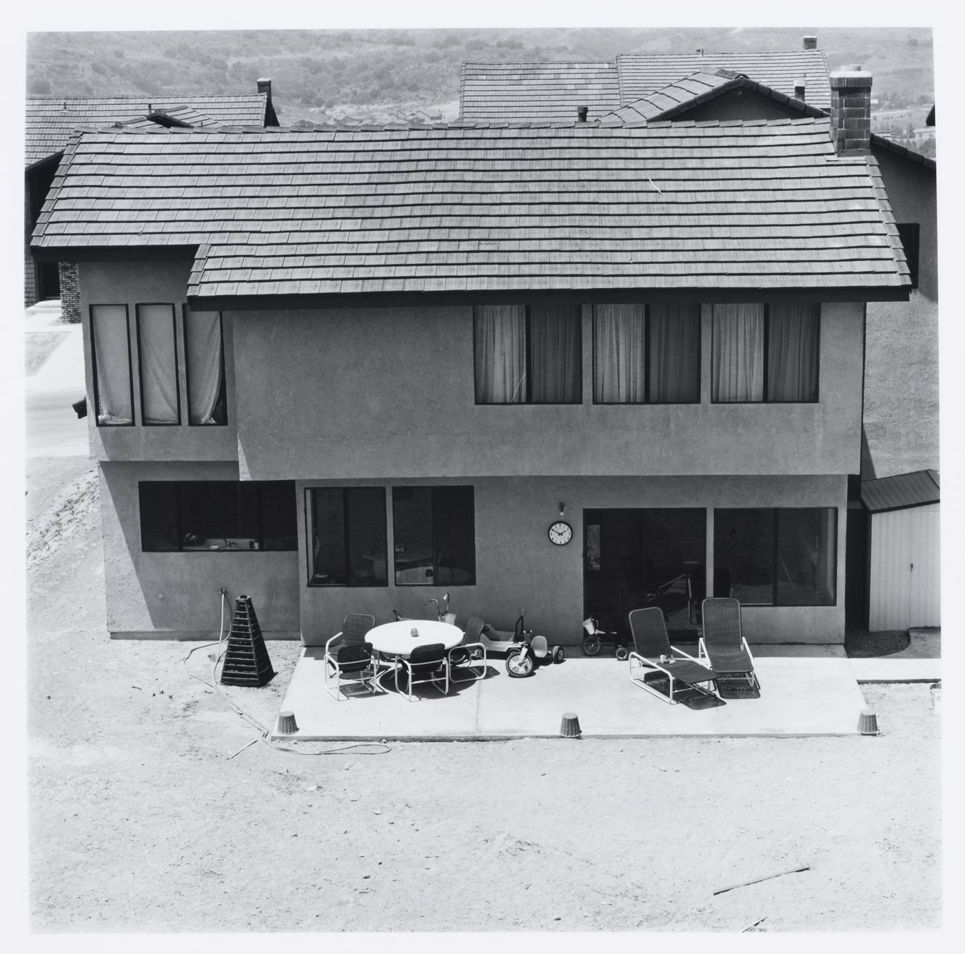 Rear of "recently occupied" stucco house showing patio and dirt backyard, Diamond Bar, California