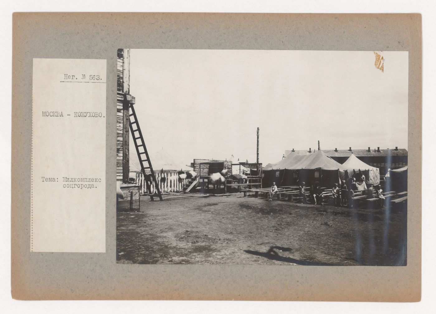 View of tents and a summer stage showing children seated on benches in the foreground and a barrack in the background, Kozhukhovo (now Moscow)