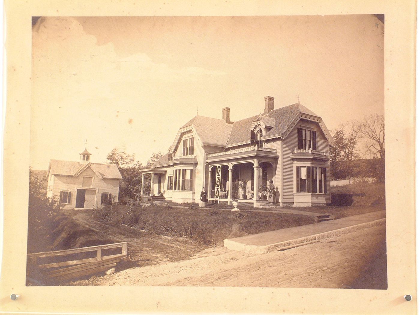 Victorian house and carriage barn, with three women outside