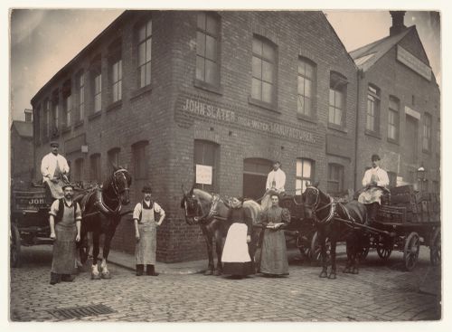 Men and women and delivery wagons in front of the John Slater Soda Water Manufacturing plant, Manchester, England