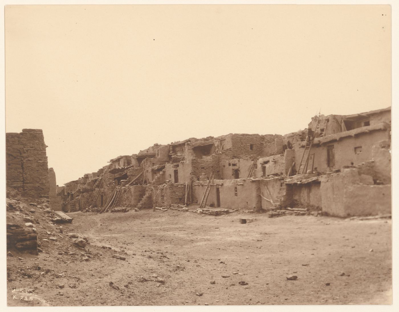 View of multi-storied houses with a person sitting on a ladder on the right, Shungopavi, Second Mesa, Hopi Reservation, Arizona, United States