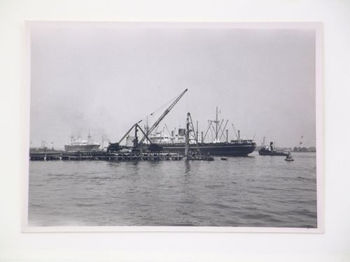 View of construction of a dock, with ships in the background