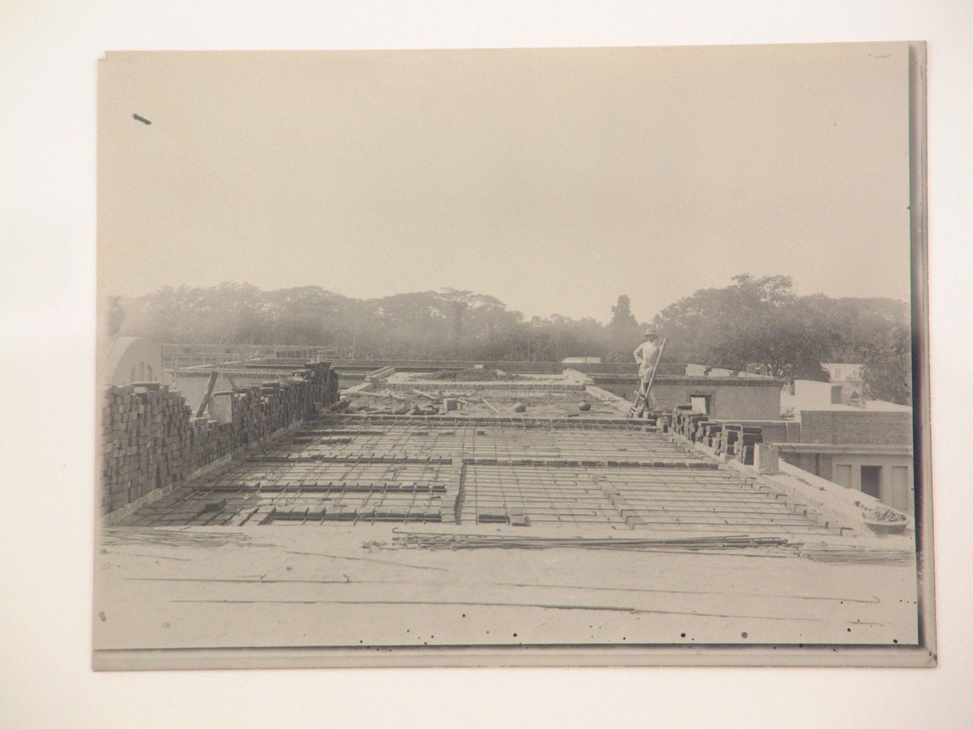 View of rooftop construction with person standing on ladder, Patna, India