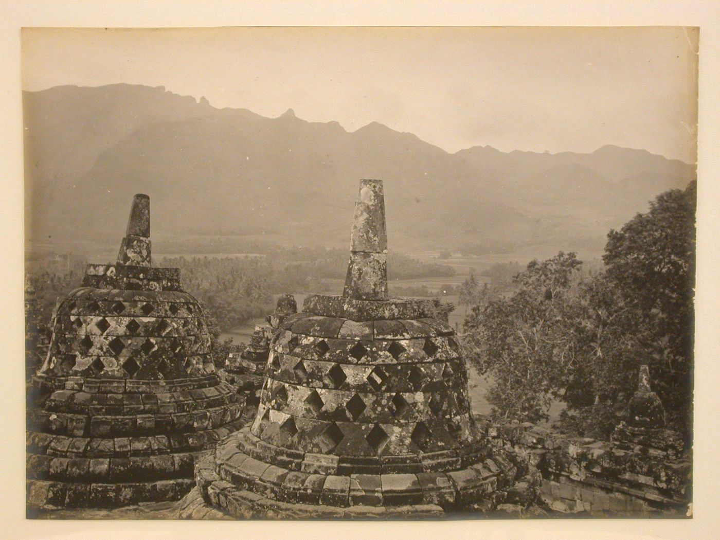 View of stone stupas on one of the upper terraces of the temple of Borobudur with the Menoreh mountains in the distance, Borobudur, Indonesia