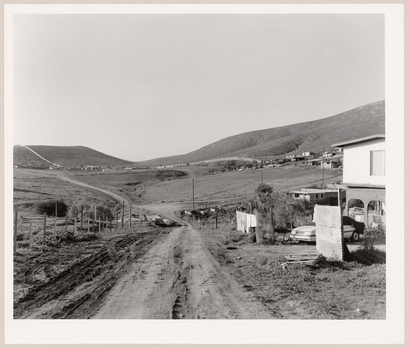 View of roads and houses with a partial view of the United States-Mexico border fence, Otay Mesa, San Diego County, California, United States, and Tijuana, Baja California, Mexico