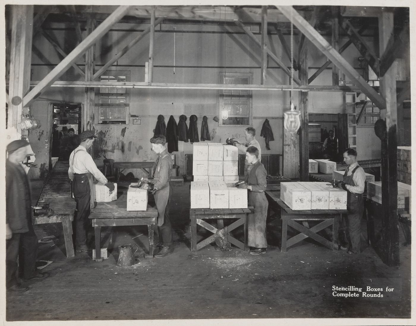 Interior view of workers stencilling boxes for complete rounds at the Energite Explosives Plant No. 3, the Shell Loading Plant, Renfrew, Ontario, Canada