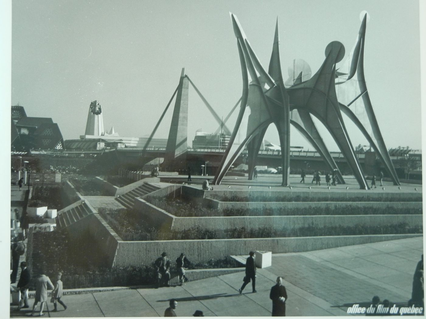 View of the sculpture 'Man, Three Disks' by Alexander Calder with Concordia Bridge and the Pavilions of Great Britain and France in background, Expo 67, Montréal, Québec