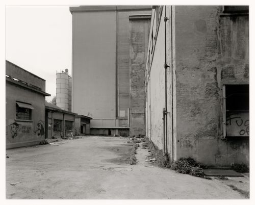 View of an alley and buildings with a silo in the left background, Malteria Adriatica, Marghera, Italy