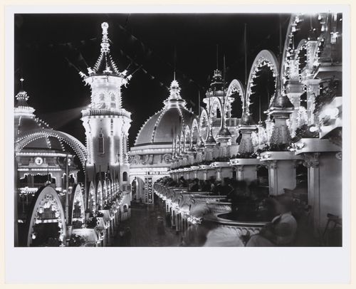Rows of balconies with seated people on right, people below, admidst [sic] lit arches and buildings at night, Luna Park, Coney Island, New York City, New York