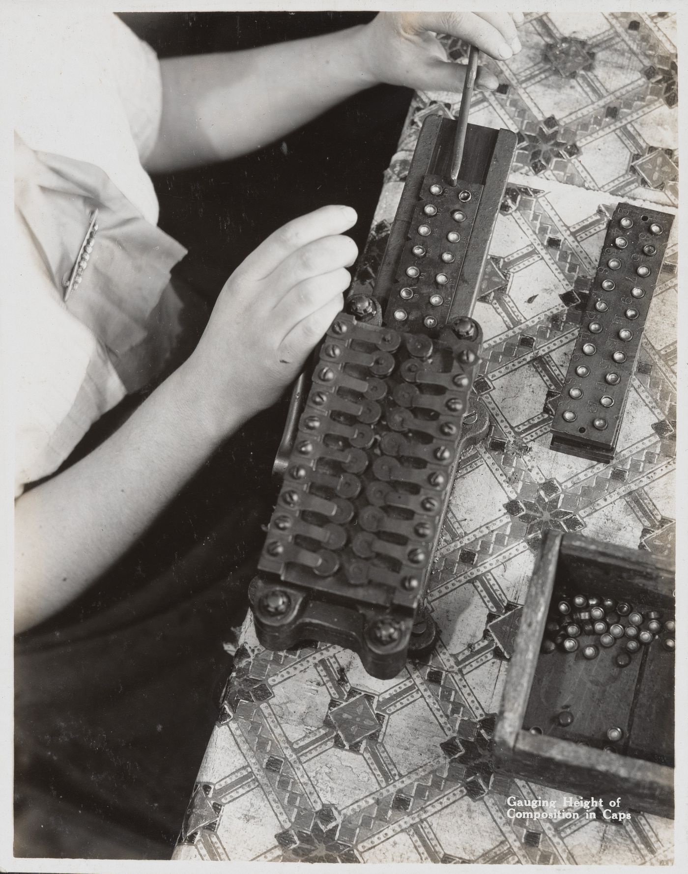 Interior view of worker gauging height of composition in caps at the Energite Explosives Plant No. 3, the Shell Loading Plant, Renfrew, Ontario, Canada