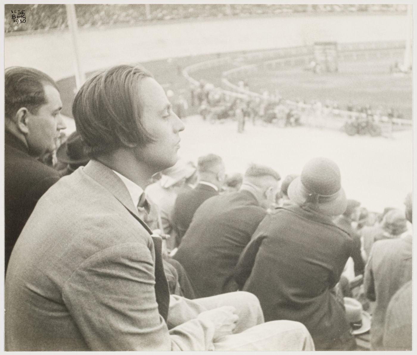Portrait of Mart Stam sitting in the grandstands at a racetrack, Frankfurt am Main, Germany