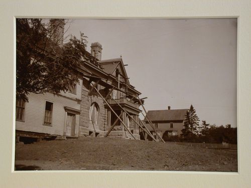Front side view of stone and wood house with scaffolding up to roof