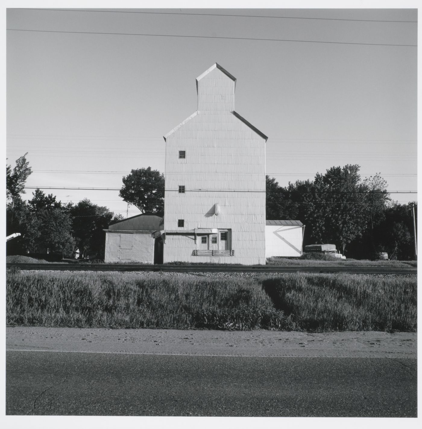 Grain elevator with corrugated metal siding, road and train tracks in foreground, Lake City, Wisconsin