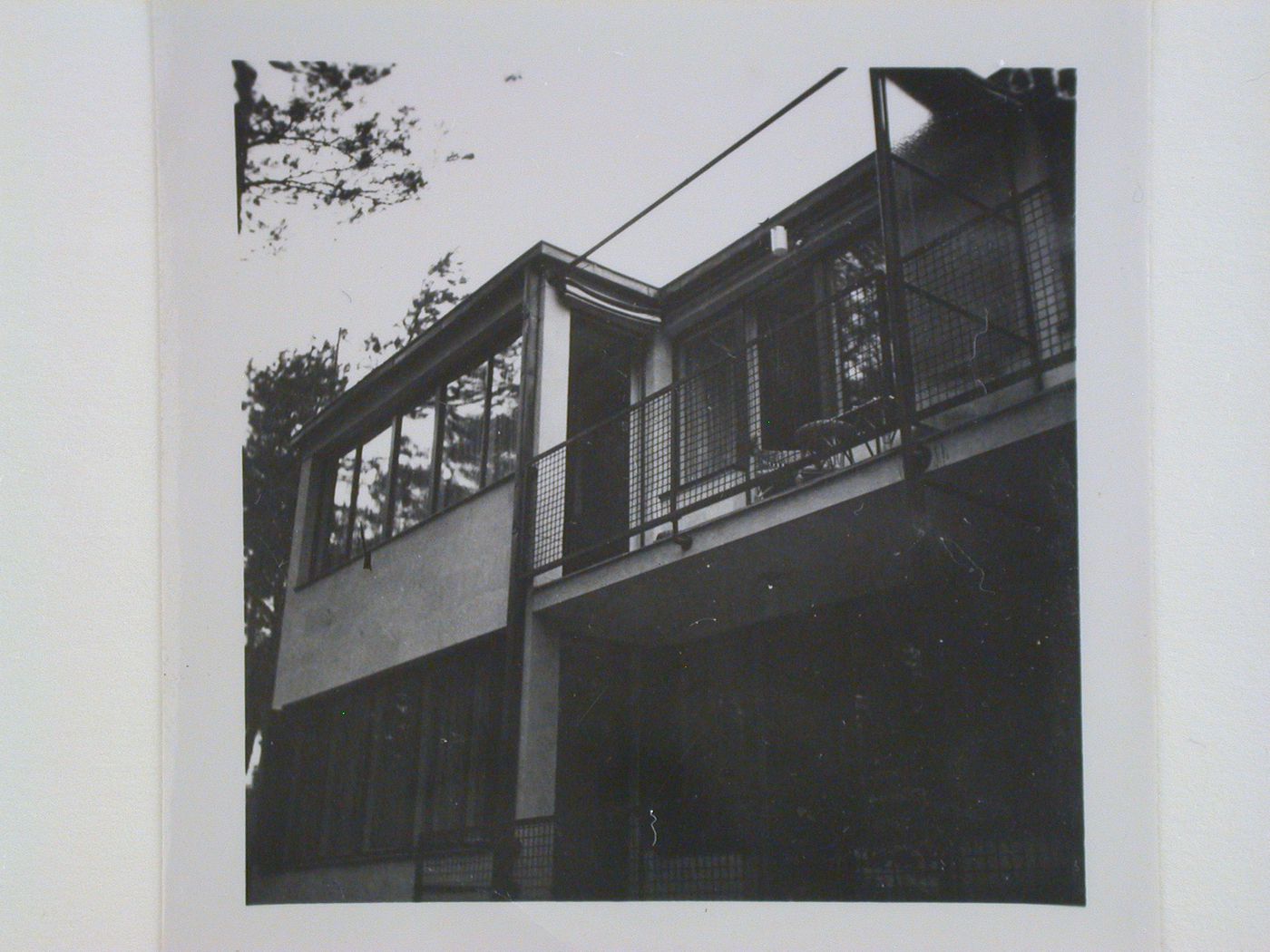 Partial view of the lateral façade of a two-storey apartment building on a wooded site