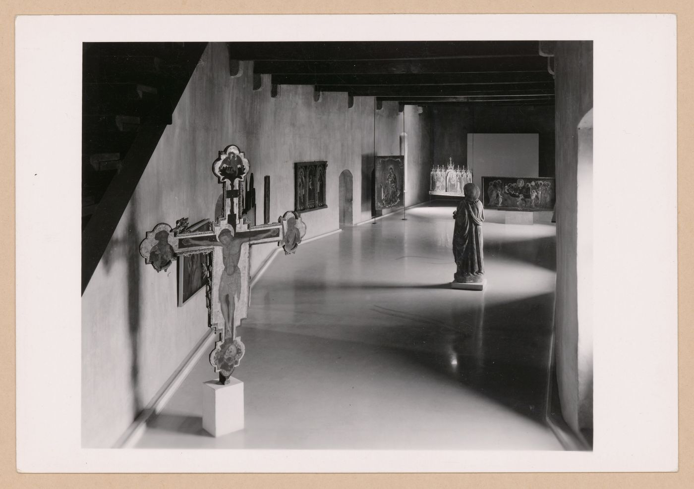 Interior view of a gallery showing a freestanding painted crucifix, a statue and paintings, Museo di Castelvecchio, Verona, Italy