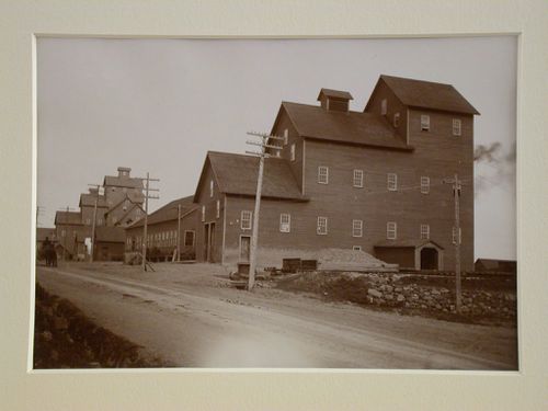 View of wooden mine shaft buildings from road, horse and cart on left