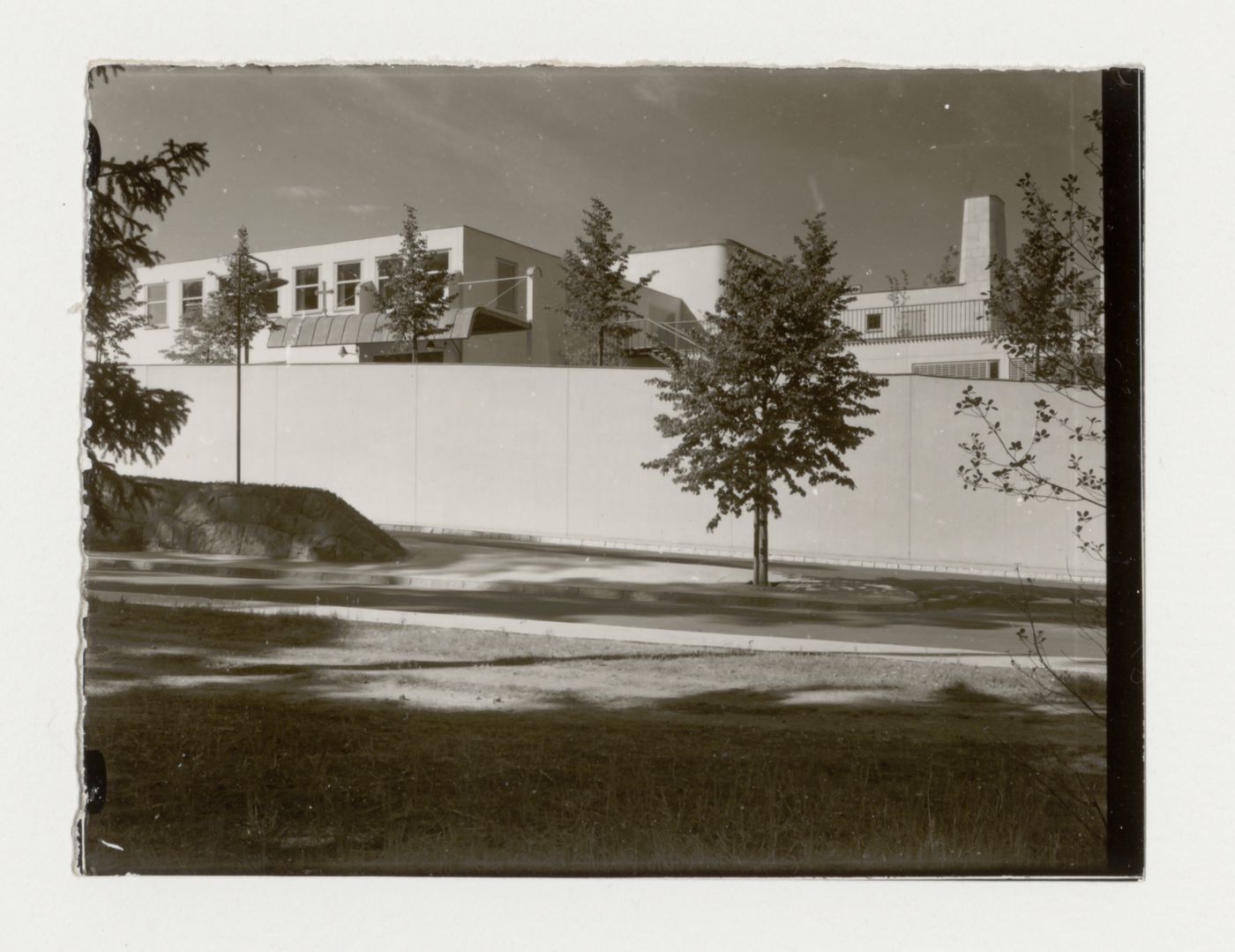 View of the rear façade of Woodland Crematorium showing the driveway and a walled garden, Stockholm