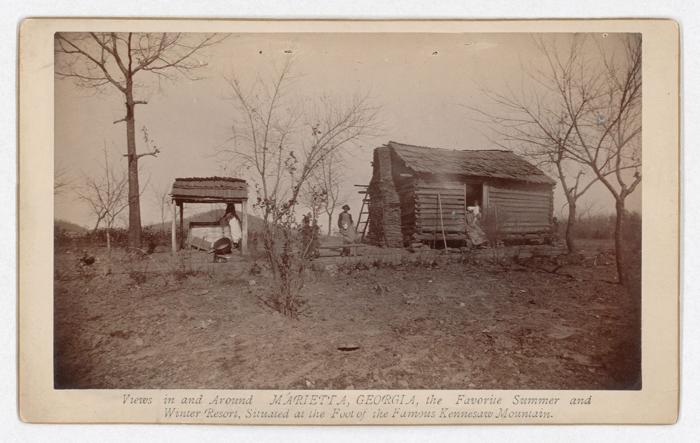 View of African American people and log cabin they live in, with covered well on the left, Marietta, Georgia, United States