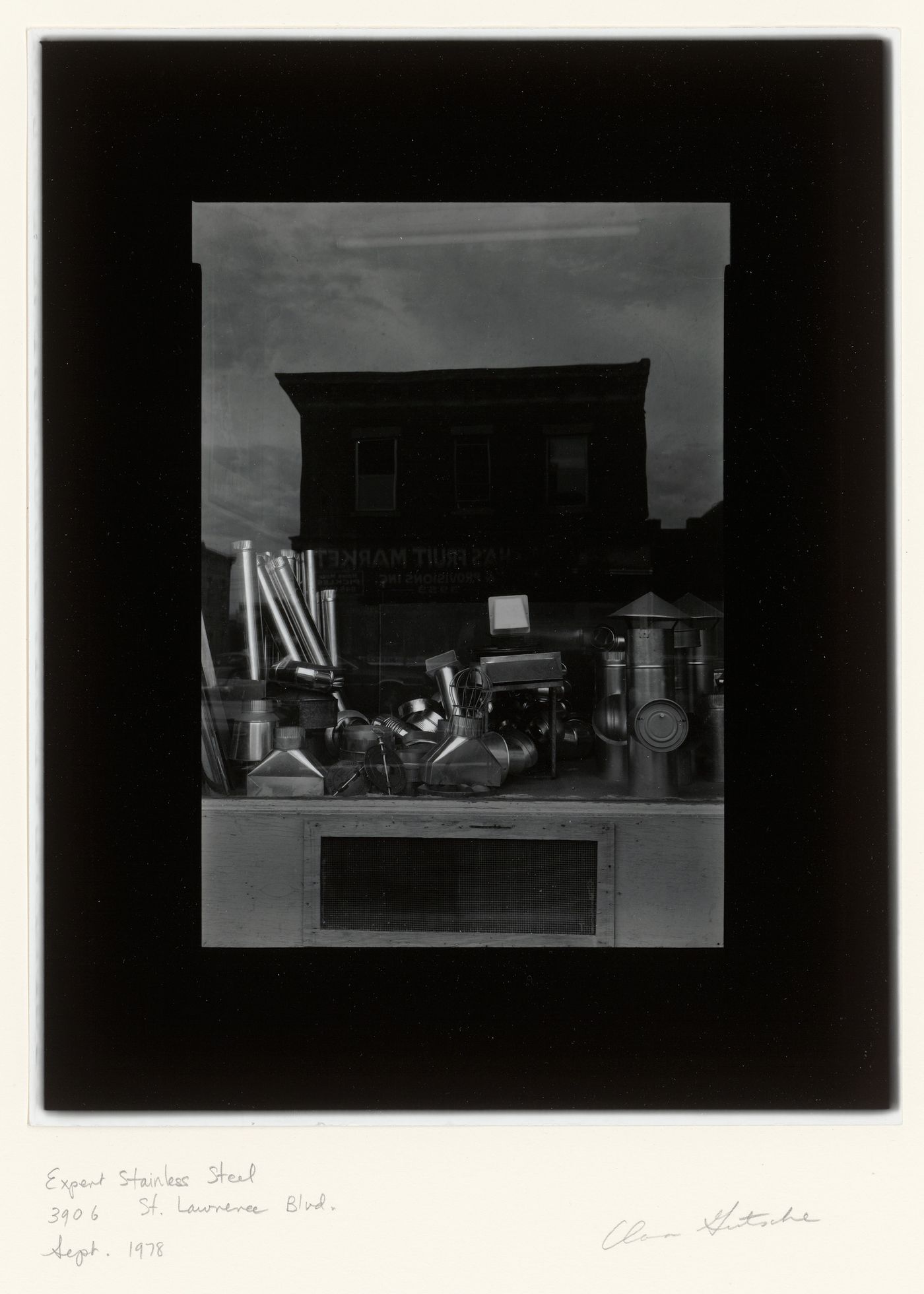 View of a display window of the Expert Stainless Steel store, showing a variety of hardware and the reflection of a fruit store across the street, 3906 boulevard Saint-Laurent, Montréal, Québec