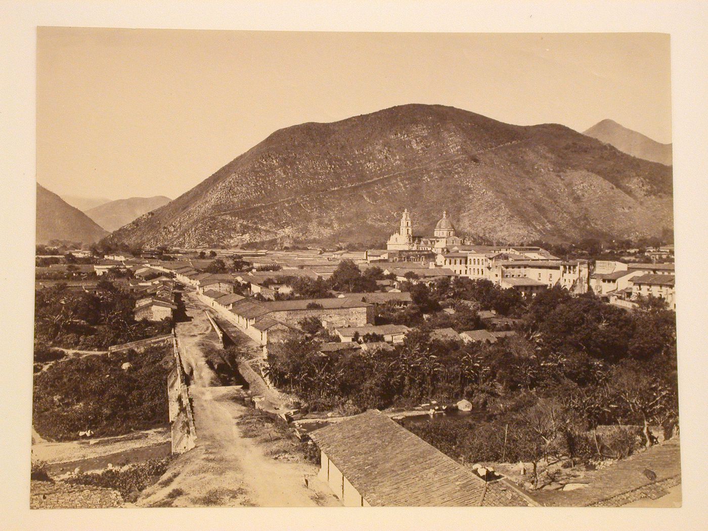 View of Orizaba showing a road and a river in the foreground and the Church of San José de Gracia and mountains in the background, Mexico