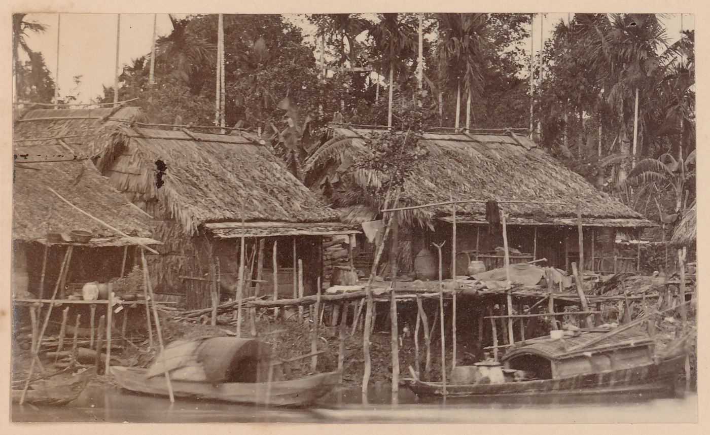 View of houses beside a river, probably in Cochin China (now in Vietnam)