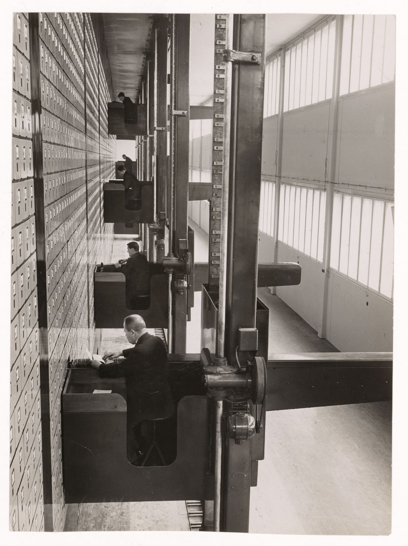 Interior view of the Central Social Insurance Institution showing men working in mobile work stations used to access the card catalog drawers, Prague, Czechoslovakia (now Czech Republic)