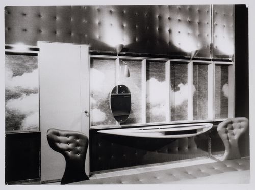 Interior view of the bedroom of Casa Rivetti showing a lacquered door; a photographic enlargement of a woodcut depicting a cloudy sky; an oval "cheval-glass"; a console with glass shelves and a divan upholstered in strawberry red chintz, Turin, Italy