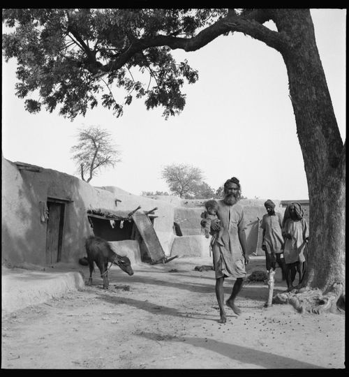 Man carrying a child in front of a rural house in Chandigarh's area before the construction, India