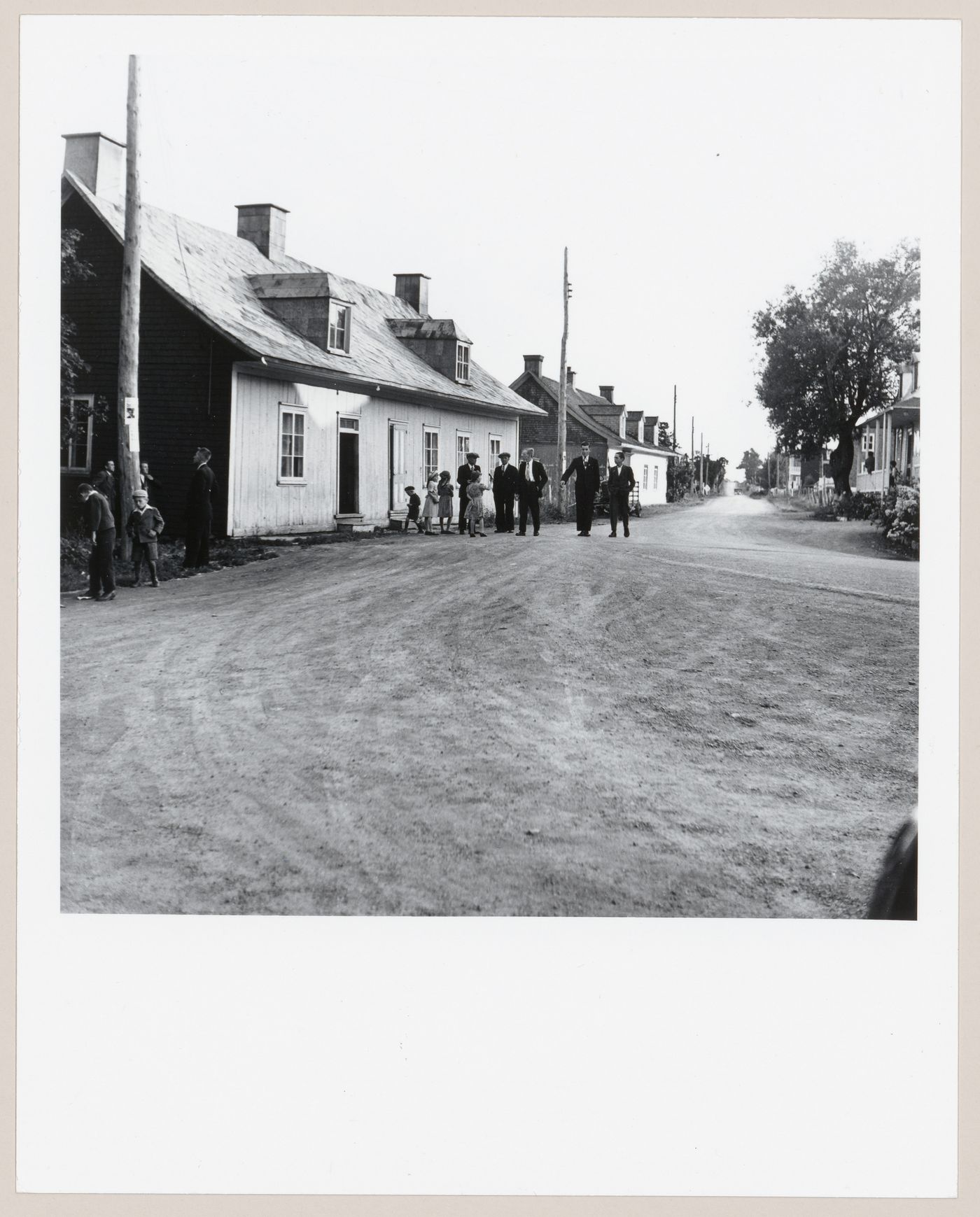 Rue d'un village, un dimanche matin, avec hommes et enfants dans leur habits du dimanche, Ile d'Orléans, Québec