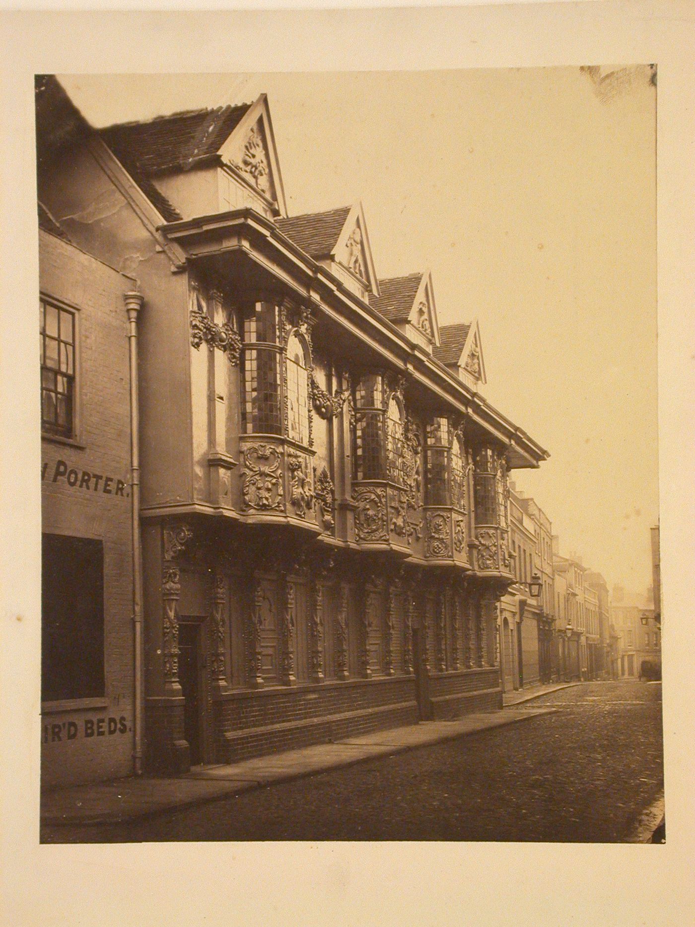 View of city street, elaborately decorated facade of 3-storey building