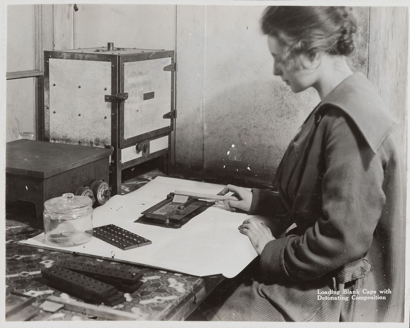 Interior view of worker loading blank caps with detonating composition at the Energite Explosives Plant No. 3, the Shell Loading Plant, Renfrew, Ontario, Canada